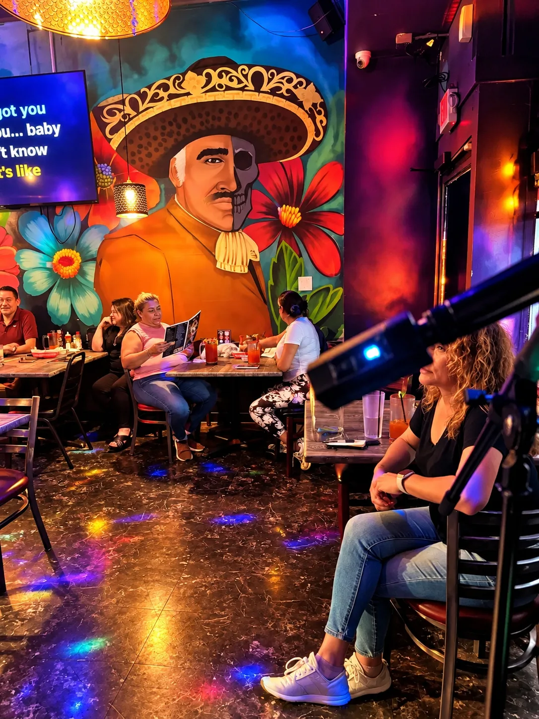 Una clienta canta con el micrófono frente a la pantalla del karaoke