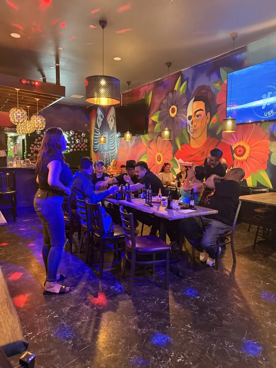 Mesas llenas y una clienta cantando junto al mural